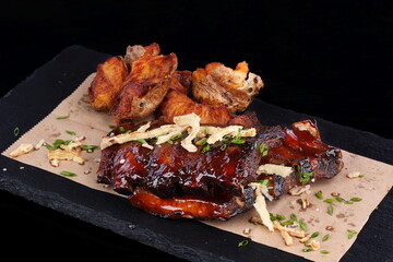 Fried ribs with vegetables on a black background