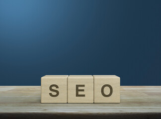 SEO letter on block cubes on wooden table over light blue gradient background, Technology search engine optimization ranking concept