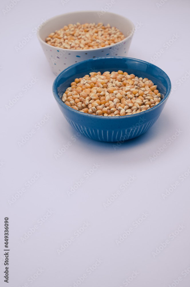 Sticker Vertical shot of corn grains on bowls isolated on light gray background