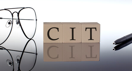 Close-up Of CIT Wooden Blocks on the black background with glasses and pen - obrazy, fototapety, plakaty