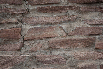 Brown stone wall background. Old masonry. Cracked wall texture.