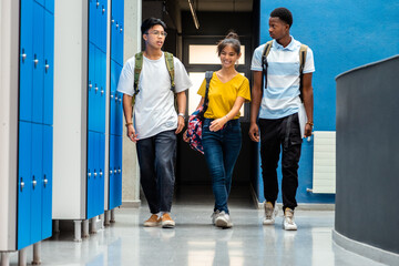 Group of multiracial teen high school students changing classes walking in school corridor. Back to school.