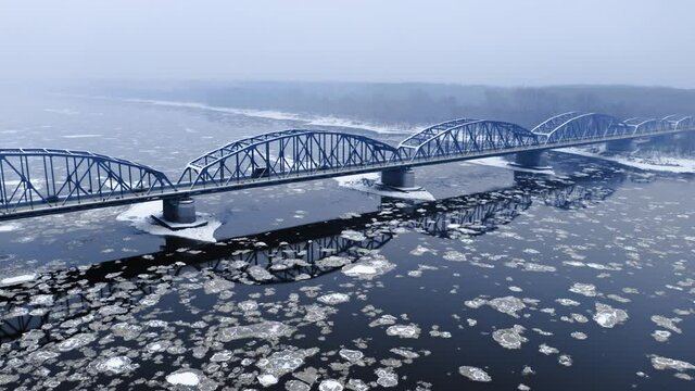 Snowy bridge and river with floe in winter.