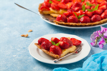 Delicious tart with strawberries on a blue painted background. Front view.