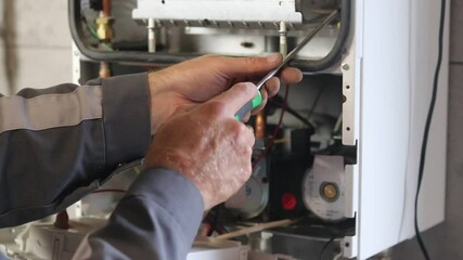 The master installs a gas boiler that hangs on the wall. The front dashboard is open. the heating is set up and started