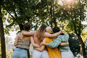 Group of four women in a park, hugging together from behind.