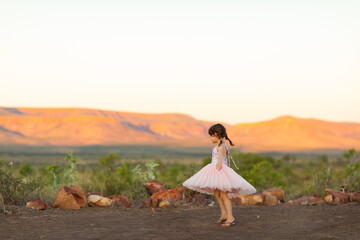 little girl outdoors swirling her pink skirt in soft evening light