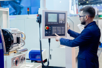 Worker man entering data in CNC machine at automatic factory floor. Modern process metal detail production going for car