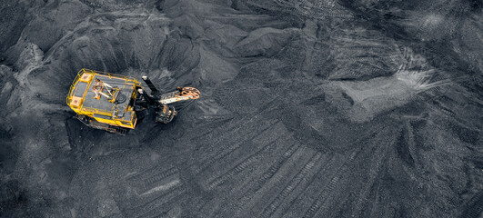 Big yellow Excavator loads coal anthracite for in open mine, banner aerial top view