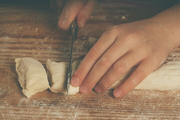 Close up young girl with a knife making homemade dumplings. Dumplings with potatoes and cheese stuffing. National food, eating, delishion, diet concept.