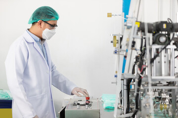 factory worker using machine control panel and producing medical face masks in factory
