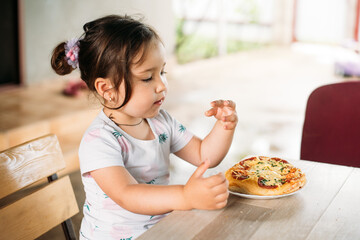 A girl, a child on the street eats a mini pizza very appetizing