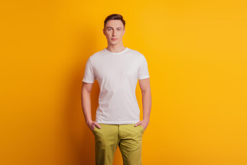 Fototapeta na wymiar Portrait of positive handsome guy arms pockets look camera posing on yellow background