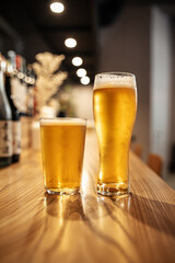 Side view on two glasses of japanese light beer on a bar desk