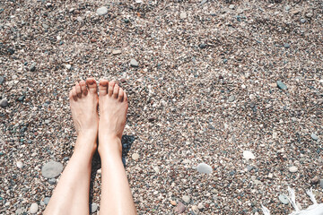 Sunbathing and relaxing girl on the sea beach. Female feet and legs on the beach under the sun. Recreation, relaxation, vacation and summer concept.