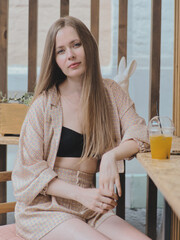 Young beauty blonde woman with gorgeous long hair enjoying free lazy time in a trendy street cafe