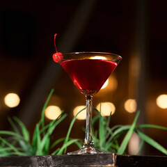 Red alcoholic shot. Cocktail glass of drink backlit on blurred background. Festive event. Nightlife concept. Side view.