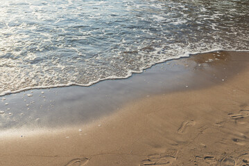 Fototapeta na wymiar Soft wave of the sea on the sandy evening beach.Soft focus,blurred image.