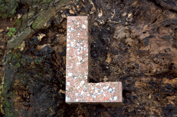 Lettera L in marmo trovata su un pezzo di legno.