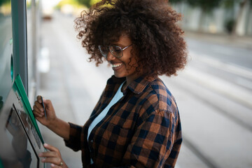 Beautiful african women using ATM machine. Attractive young woman withdrawing money from credit card at ATM.