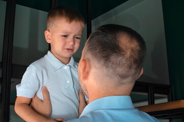 A loving dad comforts a crying son, supports a young son in a state of stress in tears, gives...