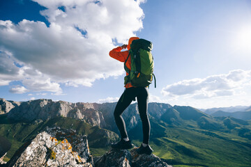 Successful woman backpacker hiking on sunset alpine mountain peak