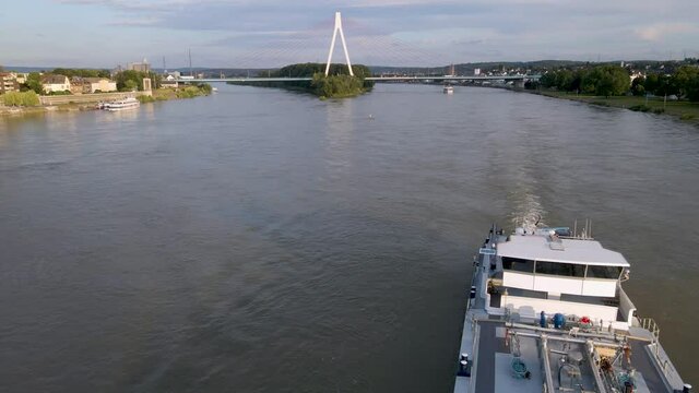 4K drone clip flying foward over a boart and towards a big bridge over the highway close to Neuwied Castle and a river next to the town of Rhineland in Germany