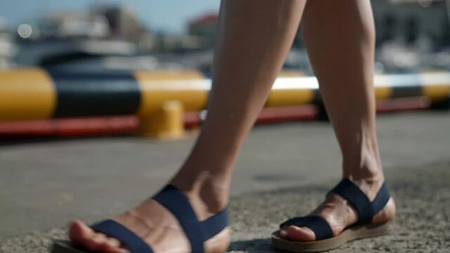 slow motion female feet in sandals close up walking on asphalt