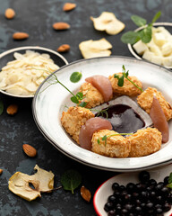 Platter with appetizer, delicious pieces in almond petals and herbs on table. Soft focus. Close-up shot. Vertical format.