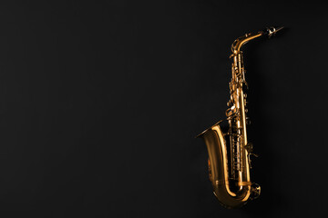 Beautiful saxophone on black background, top view. Space for text