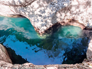 A bright turquoise river that reflects the sky flows between smooth relief canyons. Incredibly beautiful southern nature