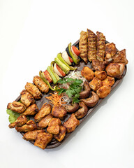 Big set of grilled meat and vegetables. Mixed food on large platter isolated on white background. Top view. Vertical format.