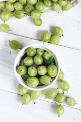 Set of organic gooseberry. Gooseberries fruits in a cup. Green gooseberry over rustic wooden background. Sweet and juicy berry. Top view.