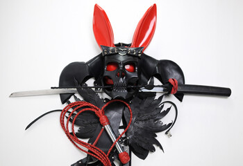 a composition of bdsm accessories masks whips belts and katanas in the form of a cross