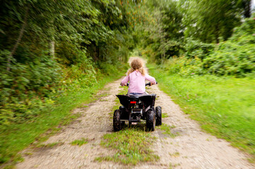 5 year old girl riding children size ATV vehicle without helmet, danger and accident concept....