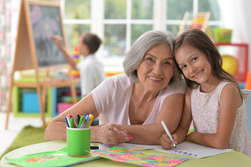 Portrait of a cute little girl drawing with her grandmother