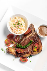 grilled T-Bone steak with coleslaw and gravy on white background