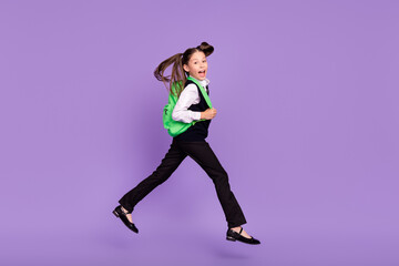 Fototapeta na wymiar Photo of glad cheerful impressed schoolgirl jump run wear rucksack uniform isolated violet color background