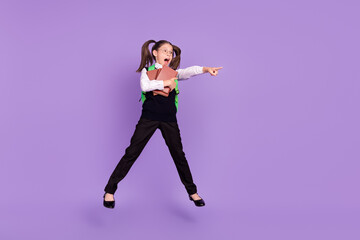 Photo of schoolgirl jump hold book direct finger empty space wear bag glasses uniform isolated purple color background