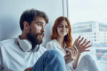 boy and girl sit near the window with headphones together apartments