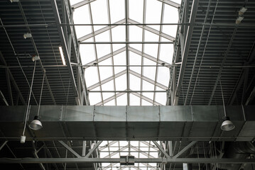 Naklejka premium Metal structure of roof shopping center, indoors. Built-in windows at the top for illumination. Architecture of large industrial building
