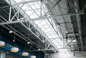 Metal roof structure of a large building, indoors. Built-in windows at the top for lighting, ventilation and lamps. Architecture and construction