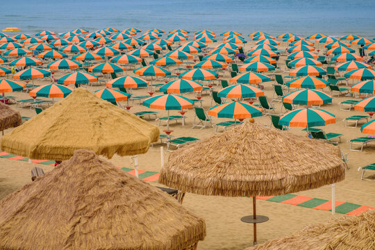 View of a sand beach full of colorful sun umbrellas without people during a sunny summer day 
