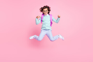 Photo of funny cheerful schoolboy jump have fun wear eyewear rucksack teal shirt isolated pink color background