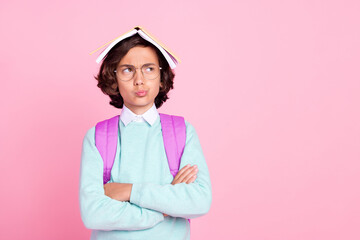 Photo of minded boy book on head folded arms look empty space wear bag teal shirt isolated pink...