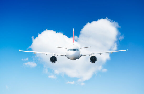 An airplane against a heart of clouds. A blue sky and a heart sign. Travel composition. High resolution photo as wallpaper.