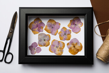 Frame with wild dried meadow flowers, scissors and thread on white background, top view