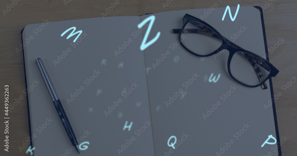 Poster multiple alphabets floating against glasses and pen on open notebook against wooden surface