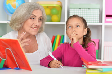 Cute little girl drawing with her grandmother