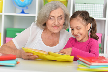Fototapeta na wymiar Little girl doing homework with her grandmother at home